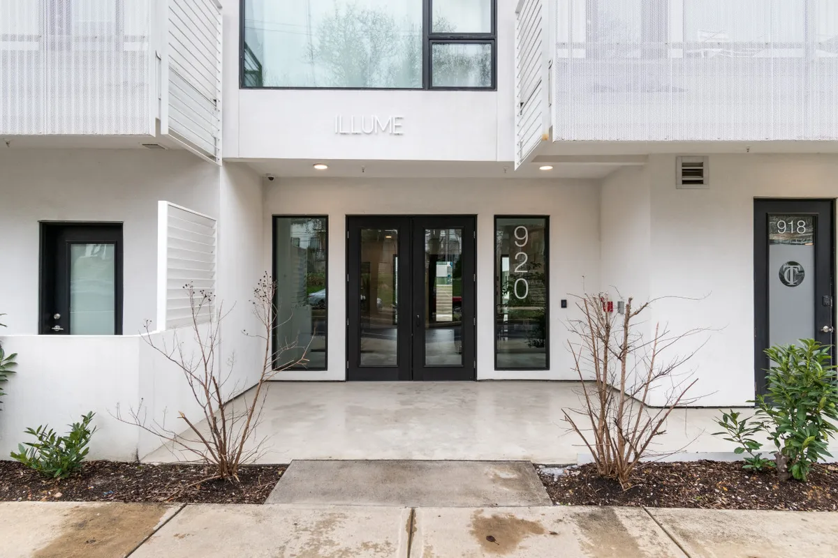 A stylish and contemporary exterior shot of Illume's main entrance, complete with modern landscaping and prominent house numbers, evoking a sense of arrival and community.