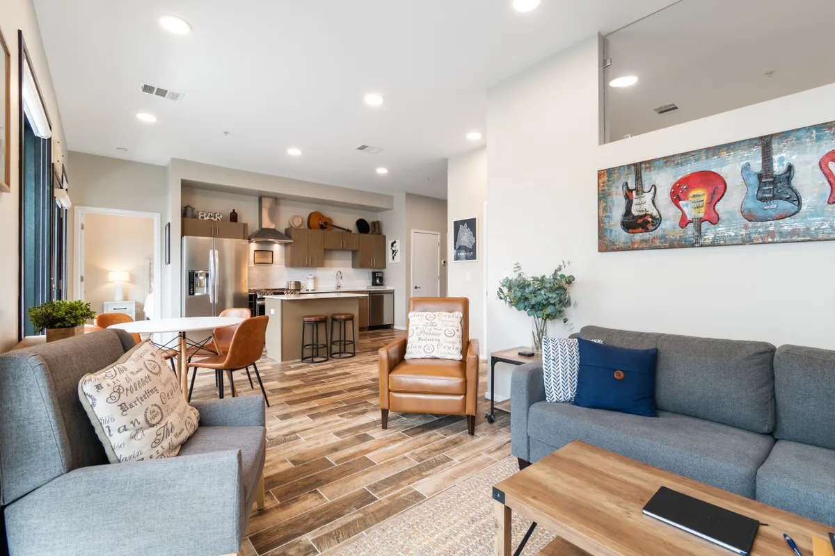 A creative and comfortable living and kitchen space featuring guitar-themed artwork, cozy seating, and an inviting kitchen area. The dining area is set for shared meals and lively conversations, while the decor hints at Nashville’s musical spirit.